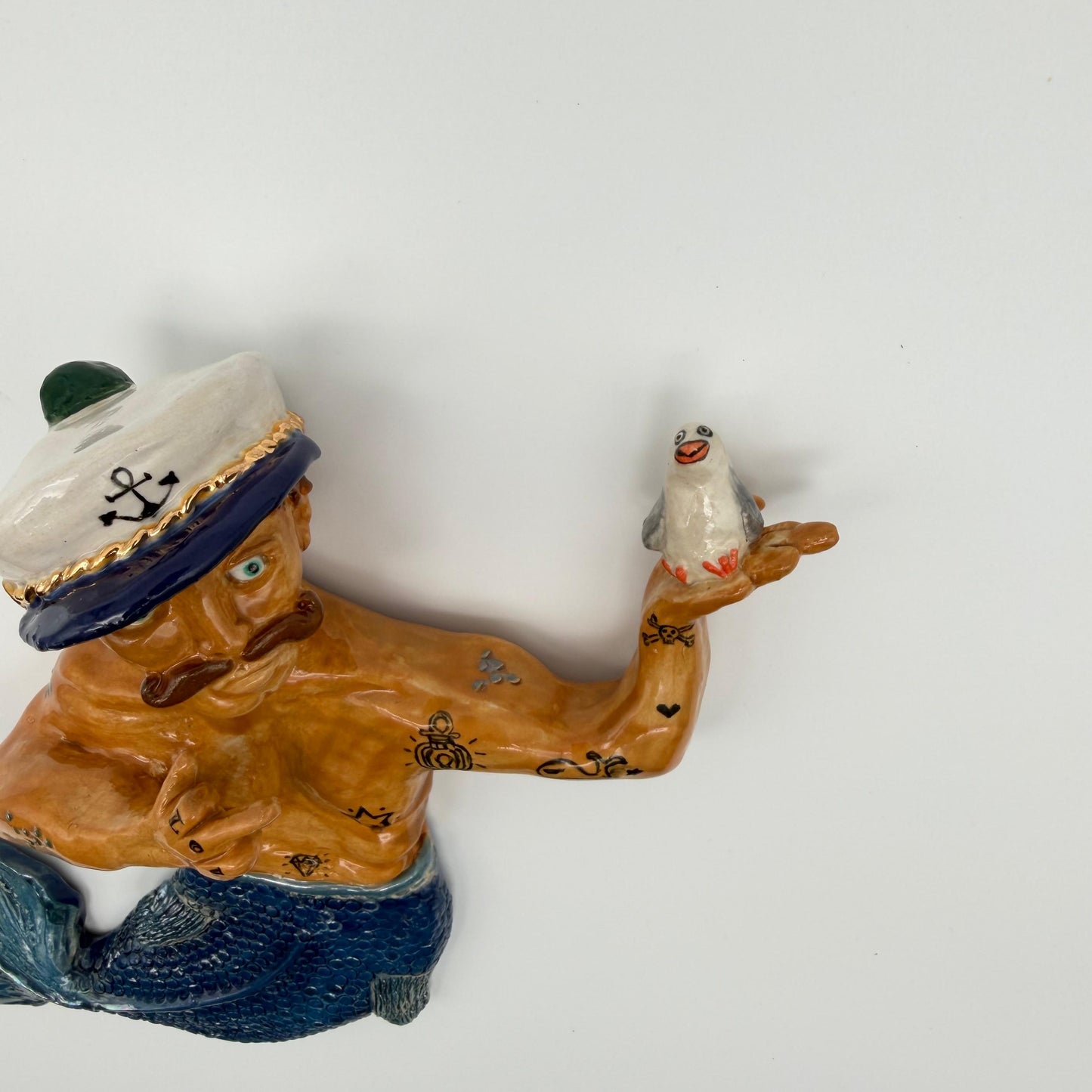 Sailor figurine with a bird on his arm against a white background