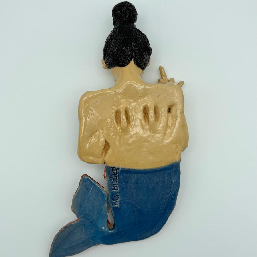 Mermaid figurine with a gold top and blue tail on a light gray background